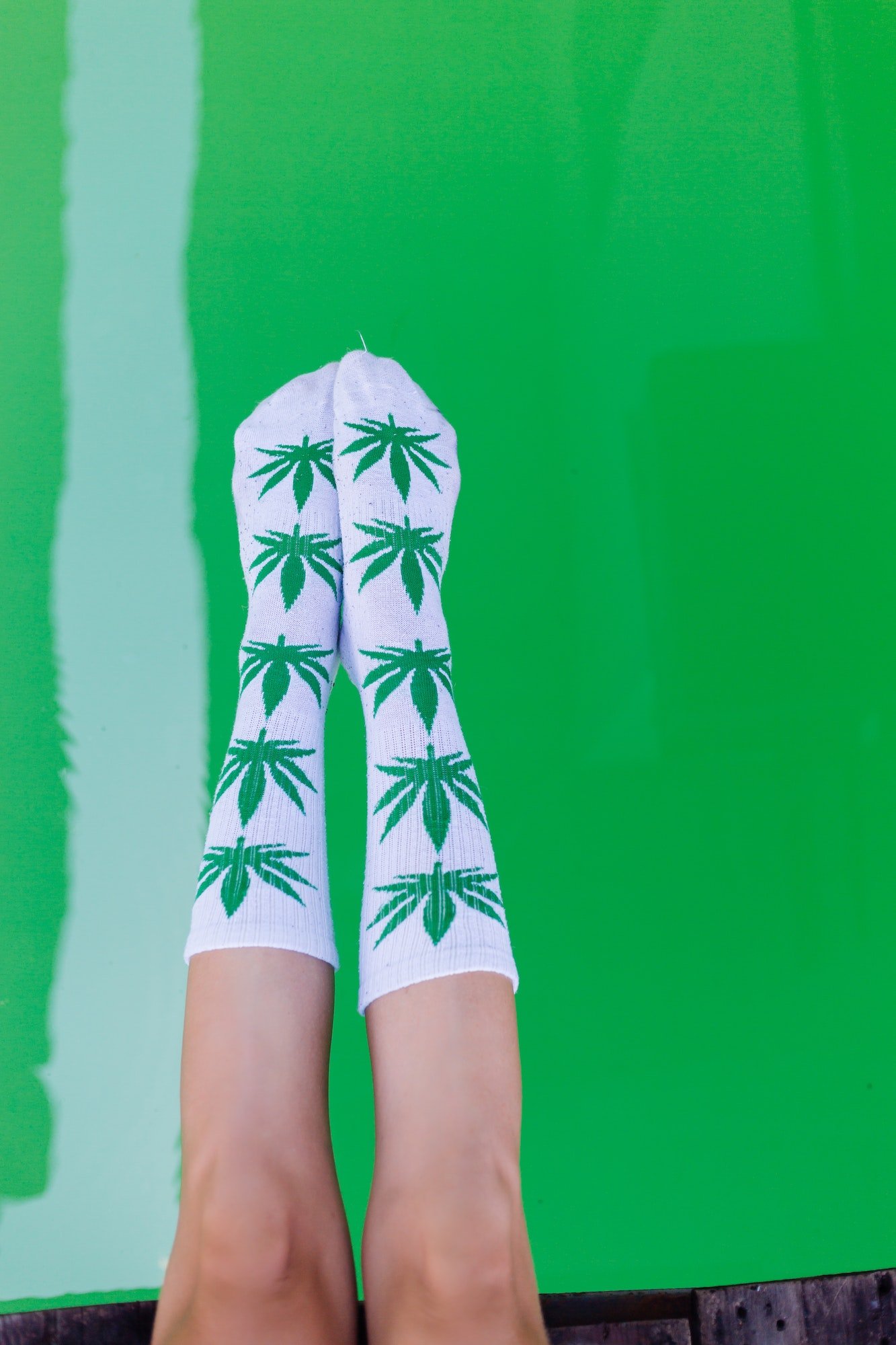 Close shot of womans legs wearing long white socks with marijuana weed print